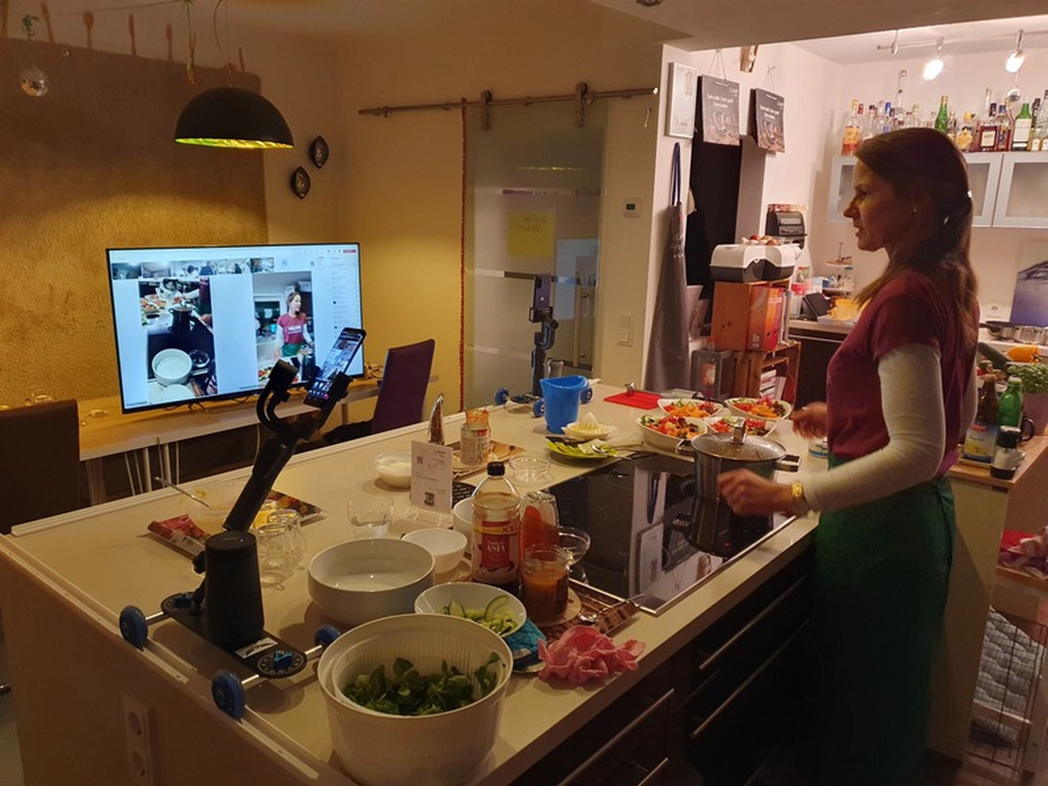 KochBAR Emsdetten – Kochstudio – Dieses Bild zeigt offenbar einen virtuellen Kochkurs oder eine Live-Übertragung einer Kochvorführung aus einer privaten Küche.