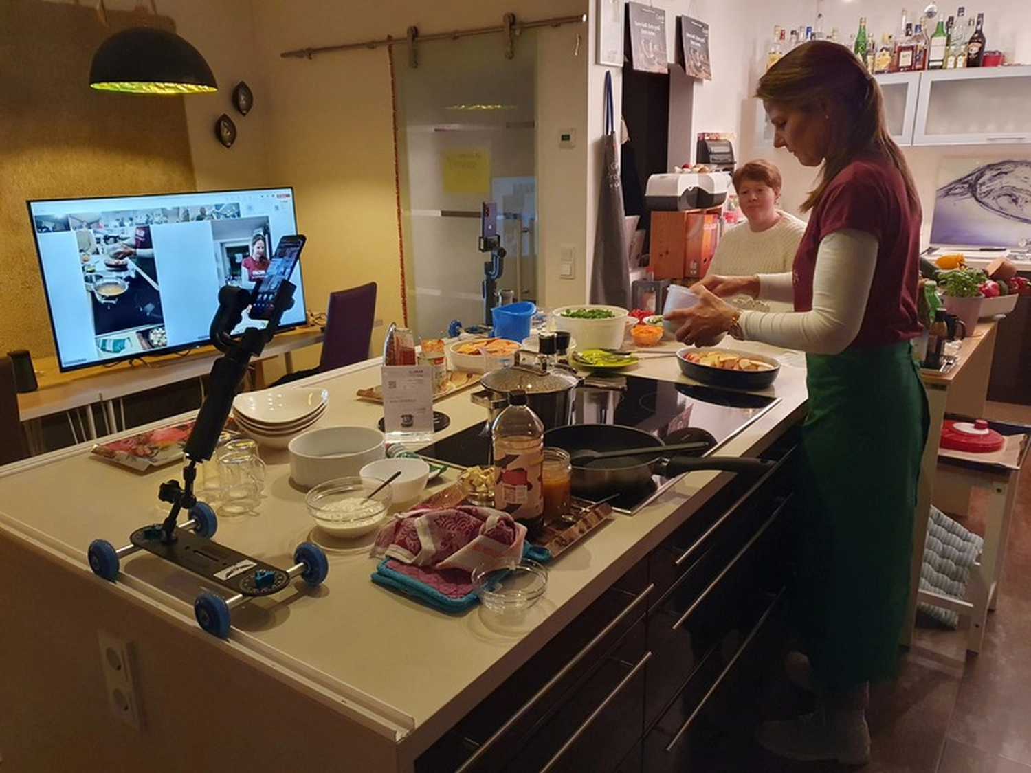 KochBAR Emsdetten – Kochstudio – Dieses Bild zeigt offenbar einen virtuellen Kochkurs oder eine Live-Übertragung einer Kochvorführung aus einer privaten Küche.